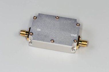 Miniature high-frequency electronic unit in closed shielding metal housing with two yellow coaxial connectors on a gray background clipart