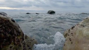 Deniz dalgaları kıyıya yakın ayrı taşların arasında