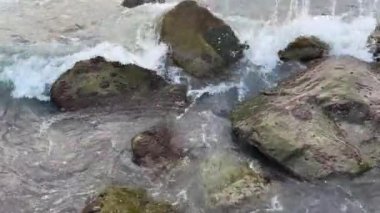 Deniz dalgaları kıyıya yakın ayrı taşların arasında