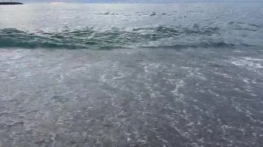 Küçük dalgalar bulutlu bir sabahta kumlu sahilde dalgalanır.