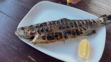 Limon suyu dökerken ızgara nehir alabalığı.