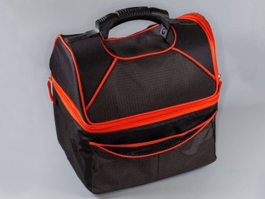 Siyah kumaş kaplamalı termal çanta, gri arka planda kırmızı fermuar ve plastik saplı.