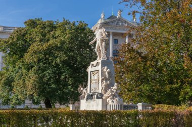 Mozart anıtı 19. yüzyılda yapıldı, şimdi Viyana, Avusturya 'da şehir bahçesinde yer alıyor. Sonbahar güneşli bir günde Hofburg 'un Yeni Şatosu ve ağaçlarının arka planına bak