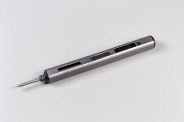Gri bir arka planda metal tüp kaplamalı elektrik kablosuz mini tornavida.