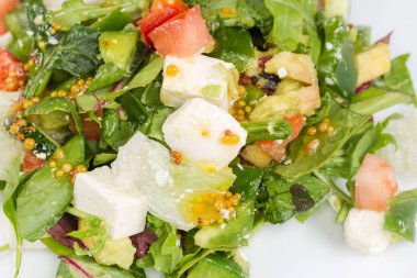 Doğranmış mozzarella salatası ve taze sebzeler, bambu masa paspasındaki farklı bir yaprak marulu, yakın çekim parçasının üst görüntüsü.