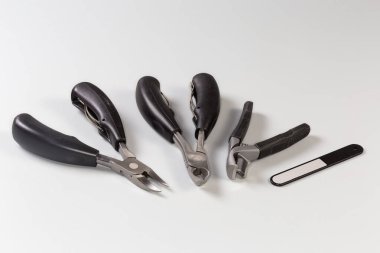 Farklı tasarım ve tırnak törpülerinden oluşan farklı profesyonel paslanmaz çelik tırnak makası seti. Gri bir yüzeyde kalın ve içe göçmüş tırnakların tımar edilmesi için. Yakın plan seçici odaklı.