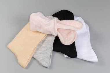 Gri bir yüzey üzerinde katlanmış, ince, günlük kadın çorapları farklı renklerdedir.