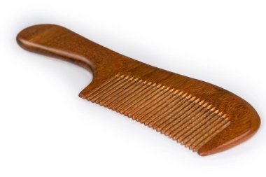 Hair comb with handle made with red wood on a white background, close-up in selective focus clipart