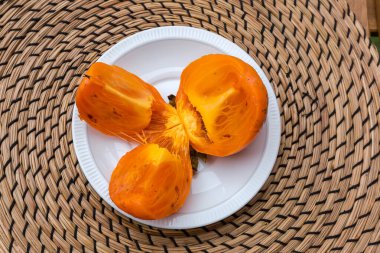 Olgun organik hurma meyveleri masanın üzerinde bir fincan tabağında üç parçaya bölünmüş haldeler ve verandada açık hava manzarası var.