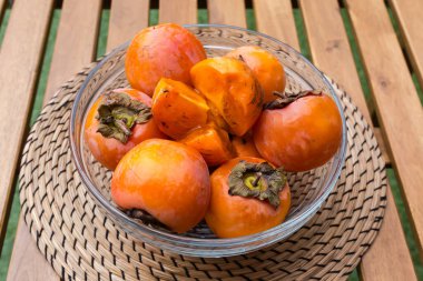 Tam ve olgun organik hurma meyveleri şeffaf cam mutfak kasesinde ahşap bir masanın üzerinde, verandada kapalı bir şekilde.