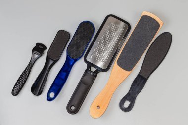 Çalışan paslanmaz çelik ve diğer aşındırıcı malzemeler, plastik ve ahşap saplı tek ayaklı bakım araçları, gri bir yüzey üzerindeki üst görünüm