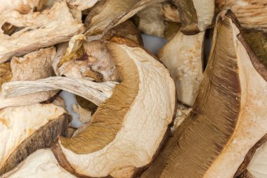 Boletus edulis 'in kahverengi başlıkları ve sapları tabağın üstüne yığılmış, yakın plan üst görüntü.