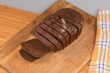 Çavdardan yapılmış kahverengi ekmeğin dilimlenmiş dikdörtgen somunu ve ahşap kesim tahtasındaki buğday unu, üst manzara.