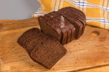 Çavdardan yapılmış kahverengi ekmeğin dilimlenmiş dikdörtgen somunu ve ahşap kesim tahtasındaki buğday unu, üst manzara.