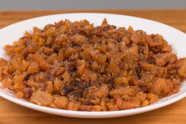 Ördek yağı ve deri dilimlerinden elde edilen çıtırtılar, beyaz bir tabakta tuz ve karabiber ile tatlandırılmış, seçici bir odak noktasında ön cephede yakın plan