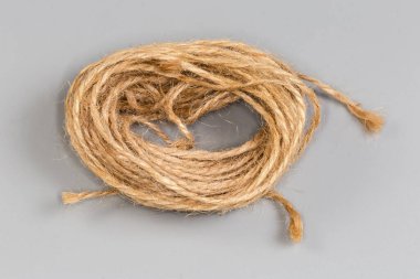 Gri arka planda, ev ihtiyaçları için doğal ağartılmamış malzemeden yapılmış kahverengi sicimin küçük bir çiziği.
