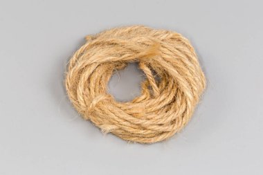 Ev ihtiyaçları için doğal beyazlatılmamış malzemeden yapılmış kahverengi sicimin küçük yuvarlak çizgileri, gri arka planda üst görünüm.