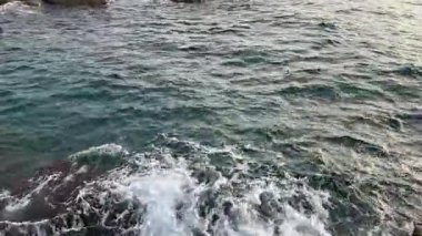 Güneşli bir sabahta kıyı kayaları arasında deniz suyu yüzeyi