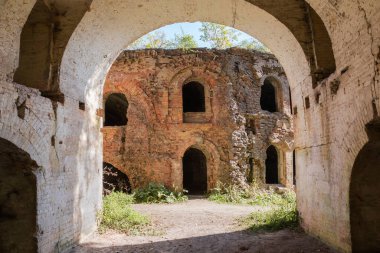 Kısmen harap olmuş, kırmızı tuğladan yapılmış, eski kalede kavisli pencere ve kapı aralıkları, sonbahar güneşli günlerinde manzara.