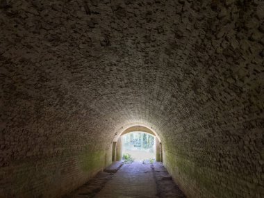 Eski kalede kırmızı tuğlalarla kaplı kemerli bir duvarla toprak duvardaki tünel.