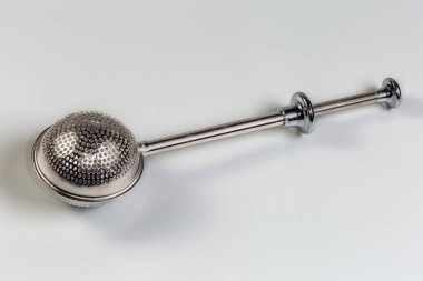 Çeşitli çay demlemek için küresel paslanmaz çelik çay süzgeci. Gri arka planda süzgeç açmak için itme kolu var.