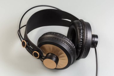 Gri bir arka planda ergonomik bantlı, modern kablolu yüksek kaliteli kulaklıklar.