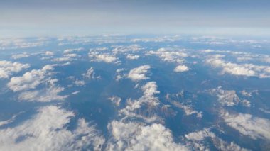 Dağların üzerinde kümülüs bulutları, uçak penceresinden manzara