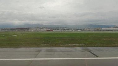 Yağmurlu havada kalkış sırasında uçak penceresinden görünüm