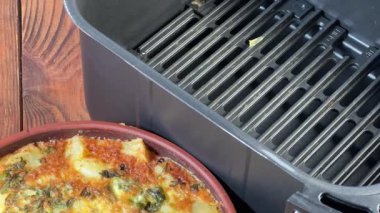 Bir kase patates güveci, kırsal masada fırın kabının yanında.