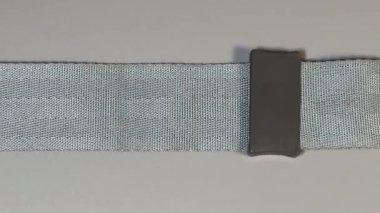 Gri arka planda emniyet kemeri, üst görünümde.
