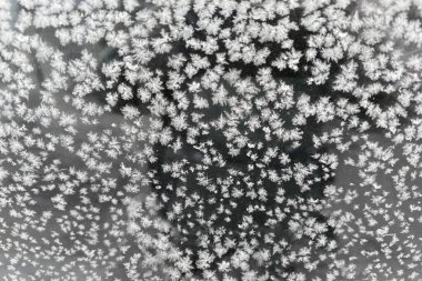 Bulutlu bir sabahta park halindeki aracın yan camının yüzeyindeki buzulun dokusu seçici odak noktasında yakın plan görüntüsü