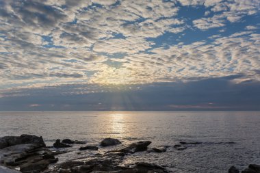 Gökyüzünün bir kısmı altokümülüs bulutlarıyla denizin üzerinde ve fırtına bulutlarıyla sonbahar sabahı bir ufuk çizgisinde.