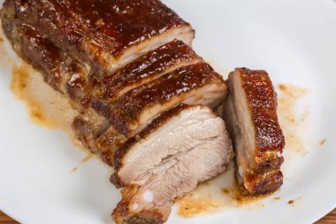Kısmen dilimlenmiş domuz pirzolası. Baharat ve özel sosla pişirilmiş. Beyaz tabakta. 