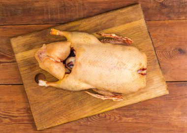 Köy tabakasında, ahşap bir kesme tahtasının üzerinde, içi oyulmuş evcil ördek leşi.