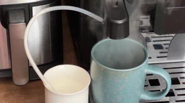 Otomatik kahve makinesinden mavi fincana donmuş süt dökülüyor.