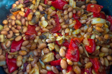 Çan biberi dilimli istiridye mantarları, doğranmış soğan ve haşlanmış fasulyeler modern kızartma tavasında pişirme yağı ile birlikte, seçici odak noktasında yakın çekim