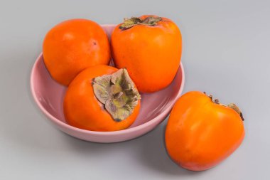 Pembe kasede olgun organik hurma meyveleri ve gri arka planda bir meyve var.