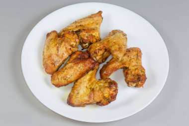 Fırında kızarmış tavuk kanadı. Gri arka planda baharat ve şifalı otlar.