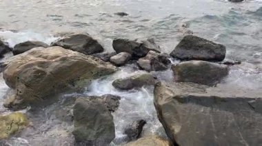 Kıyıya yakın taşlar bulutlu deniz suyuyla yıkanır.