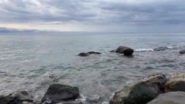 Bulutlu bir sabahta bulutlu gökyüzüne taş kıyısı olan deniz.