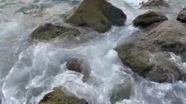 Kıyıya yakın taşlar bulutlu bir sabahta deniz suyuyla yıkanır.