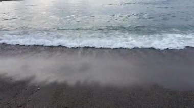 Bulutlu bir sabahta kumlu sahilde deniz sörfü
