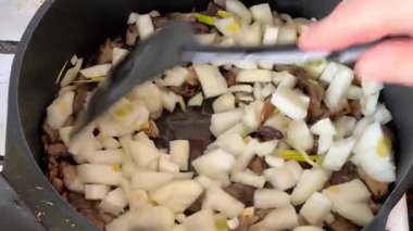 Kızartma tavasında soğanlı spatula istiridye mantarıyla karıştırılmış.
