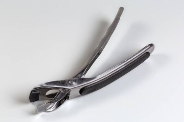 Fırınlardan sıcak tabakları güvenli bir şekilde çıkarmak için maşa şeklinde paslanmaz çelik mutfak tutacağı, gri bir arka plan.