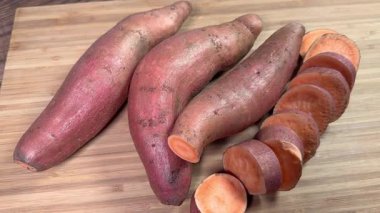 Kesme tahtasının üzerinde tam ve dilimlenmiş çiğ patates çubukları.