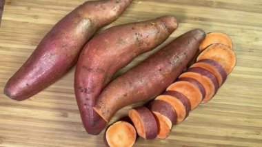 Kesme tahtasının üzerinde tam ve dilimlenmiş çiğ patates çubukları.