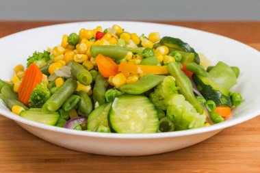 Farklı sebzelerin taze kaynatılmış karışımı bir tabakta, ön cephede seçici odak noktasında.