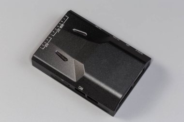 Düz dikdörtgen plastik kaplamalı küçük bir elektronik ünite. Çevrede çeşitli elektrik konnektörleri bulunuyor ve bunların üzerinde gri bir arkaplan bulunuyor.