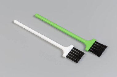 Gri arka planda düz beyaz ve yeşil plastik saplı sert siyah plastik tüylü iki manuel fırça.