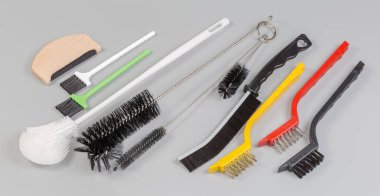 Çeşitli amaçlar için farklı el fırçaları, farklı kıllar, gri arka planda plastik ve metal malzemelerle yapılmış farklı sertlikler.